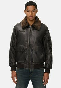 Schwarze Lederbomberjacke mit einem braunen Pelzkragen, zwei Fronttaschen, Reißverschluss und gerippten Bündchen. Glatte Textur und strukturierter Schnitt.
