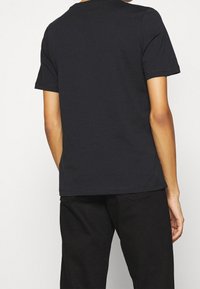 Zwarte katoenen T-shirt met een ronde hals, korte mouwen en een rechte snit. Kenmerkt zich door minimale stiksels en een gladde textuur.