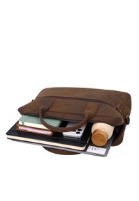 Brown leather briefcase partially open showing notebooks, smartphone, laptop, and wooden water bottle inside.