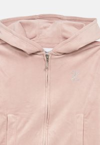 Mehakasto roza velour zip-up dukserica s dvema sprednjima žepoma, kovinskim zadrgo in majhnim kamenčkom s monogramom na levem prsnem delu.