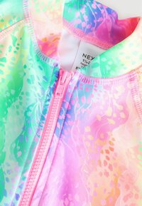 Costume da bagno multicolore con una sfumatura pastello di rosa, verde e blu, dotato di una zip frontale e di un design testurizzato e pattern.