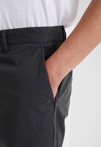 Černé bavlněné kalhoty se rovnými nohavicemi, s postranními kapsami. Materiál má hladkou strukturu a pohodlný střih.