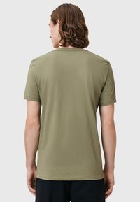 T-shirt verde oliva a maniche corte con collo a giro, realizzato in tessuto morbido. La vista dal retro mostra una texture liscia e senza dettagli prominenti.
