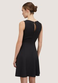 Schwarzes ärmelloses Kleid mit einem figurbetonten Oberteil, weit schwingendem Rock und einem Rückenschlitz mit Knopfverschluss. Glatte Textur, elegante Silhouette.