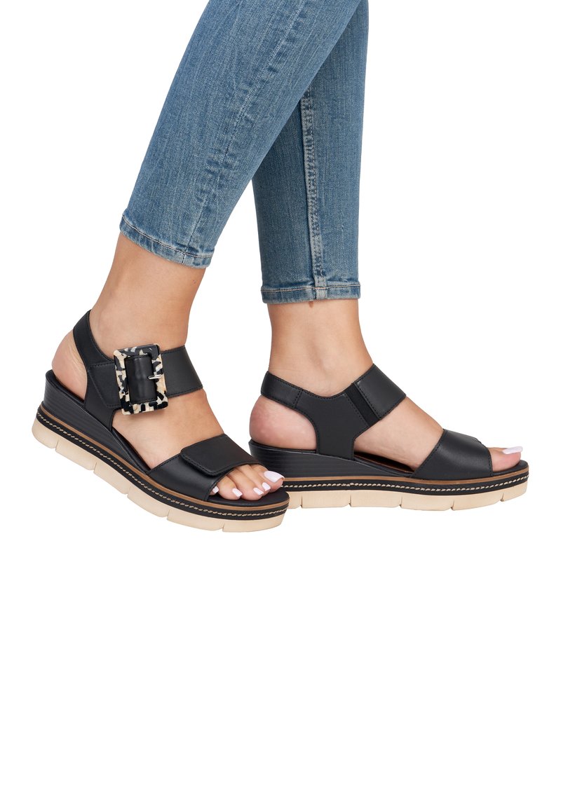 Sandales à talon noir avec un design à bout ouvert, ornées d'une boucle imitant un motif léopard et d'une semelle beige légère à finition texturée.