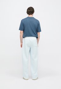 Μπλε πουκάμισο με κοντά μανίκια συνδυασμένο με ανοιχτό μπλε, άνετο παντελόνι με πίσω τσέπη και μαλακό, υφασμάτινο ύφασμα.