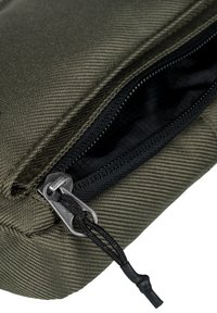 Borsa di tessuto verde oliva con una superficie texture, dotata di una cerniera nera con un tirante argentato e un accento in corda nera.