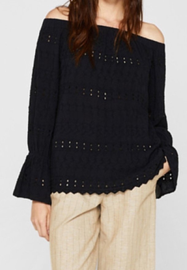 Sort off-the-shoulder bluse med broderet detaljer, lange klokkeærmer og en bølget kant. Båret med lyse stribede bukser.