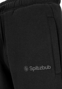 Zwarte joggingbroek van zachte stof, met een zijzak en een tonale logo die op het dijbeen is gestikt. Elastische tailleband voor comfort.