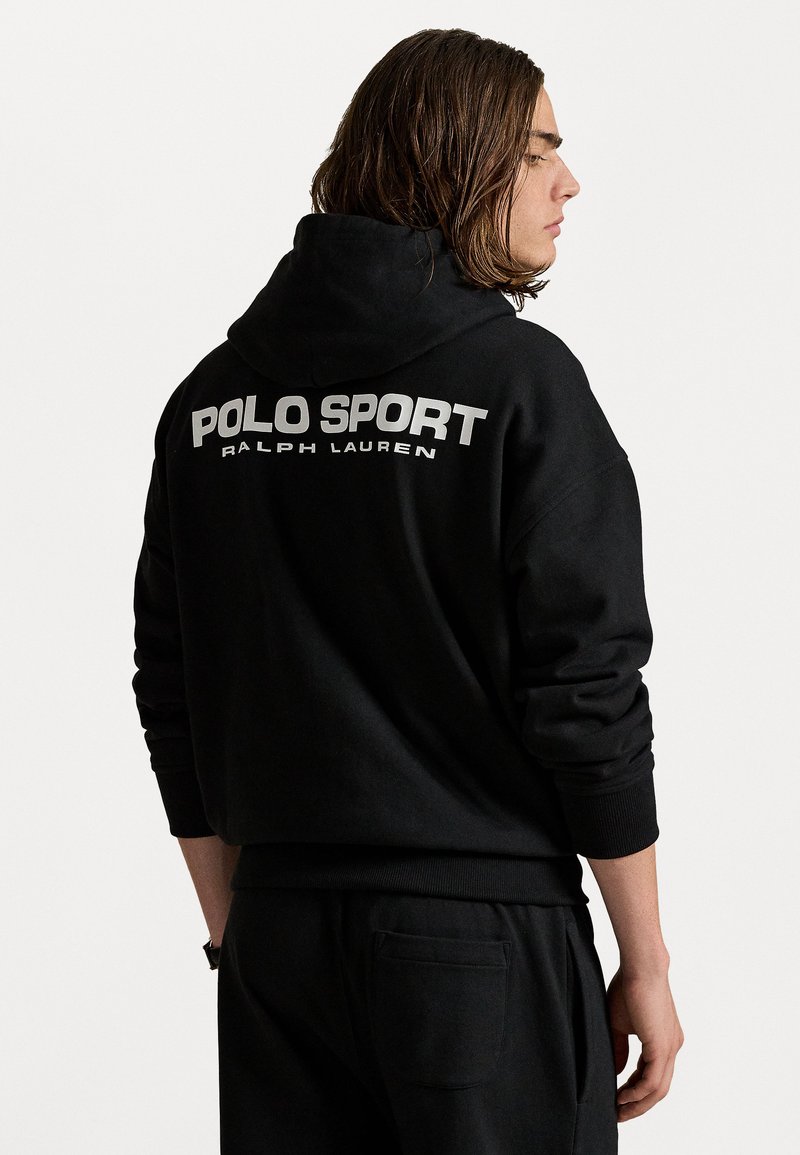 Mustvalge kapuutsiga jope, mille seljal on suur valge "POLO SPORT" logo. Kanga pehmus ja lõtv istuvus koos soonikkäistega.