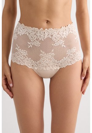 Ropa interior de encaje beige de talle alto con motivos florales, usada por una persona, mostrando la zona media y los muslos superiores sobre un fondo liso.