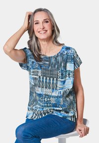 Kurzes, kurzärmliges Oberteil in Blau und Schwarz mit einem Rundhalsausschnitt, das eine Mischung aus geometrischen und abstrakten Mustern zeigt. Weicher Stoff.