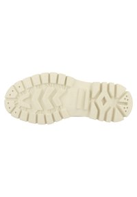 White rubber shoe sole featuring a rugged tread pattern with various textured segments and grooves for traction and stability.