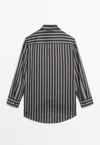 Czarna i biała koszula w paski z długimi rękawami, kołnierzykiem i zaokrąglonym dołem. Posiada cienkie poziome i pionowe paski o gładkiej fakturze.