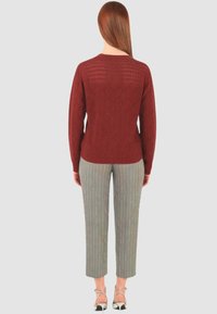 Maglione bordeaux a trama con motivo a rombi, abbinato a pantaloni cropped a righe grigio chiaro e sandali con tacco e cinturini.