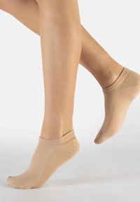 Calzini alla caviglia beige realizzati in un tessuto liscio e elastico con un bordo a costine. Presentano un design semplice e un taglio a profilo basso.