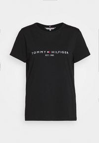 Černé krátké rukávy bavlněné tričko s nápisem "Tommy Hilfiger EST. 1985" a červeno-bílo-modrým vlajkovým logem umístěným na hrudi.