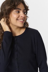 Tmavě modrý kardigan s kulatým výstřihem, dlouhými rukávy a zapínáním na knoflíky. Tkanina vypadá jako ribetová s jemnou texturou.