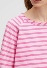 Rosa gestreifter Pullover mit Rundhalsausschnitt, weichem Material und Raglanärmeln mit abwechselnd kräftigen und sanften Streifen.