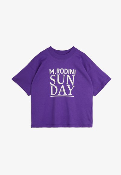 Purple short-sleeve t-shirt featuring a white graphic print that reads "M. RODINI SUNDAY" centered on the front. Soft fabric texture.