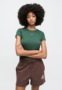 Πράσινο βαμβακερό μπλουζάκι με στρογγυλή λαιμόκοψη και κοντά μανίκια, συνδυασμένο με καφέ βαμβακερά σορτς που διαθέτουν κορδόνι στη μέση και τυπωμένο λογότυπο.