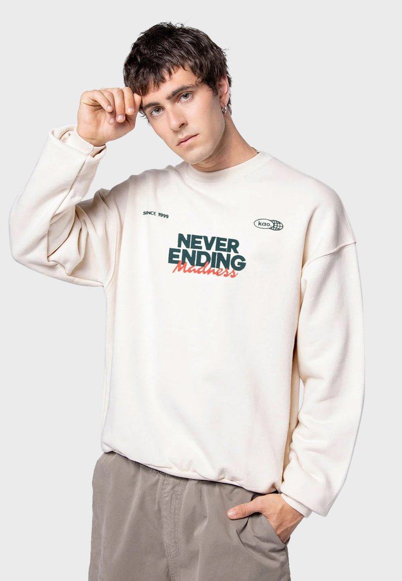 Lichtbeige sweatshirt met de grafische tekst "NEVER ENDING Madness" in groen en rood. Relaxed fit met ribgebreide manchetten en onderkant.