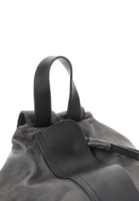 Sac en cuir gris avec une texture douce, présentant une forme arrondie, de courtes poignées et un détail en patch lisse sur le devant.