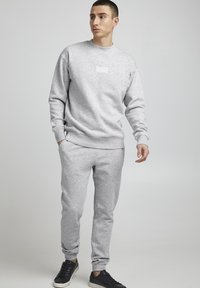 Grijze sweatshirt met een ronde hals, gecombineerd met bijpassende joggers. Beide gemaakt van zachte stof, met ribgebreide boorden en een logodetail.