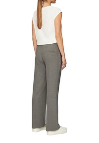 Szare szerokie spodnie o teksturowanej tkaninie, z tylną kieszenią. Połączone z białą koszulą z krótkim rękawem i białymi trampkami.