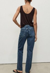 Top marrón sin mangas y pantalones vaqueros rectos azules. Los pantalones tienen un diseño clásico con dos bolsillos traseros y un acabado desgastado.