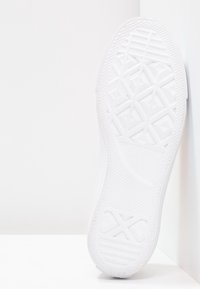 Semelle de chaussure en caoutchouc blanc avec motif de bande de roulement géométrique, présentant des bords arrondis et un logo en relief. Texture lisse, design léger.