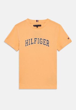 Oranžna bombažna majica s temnomodrim napisom "HILFIGER" čez prsa, kratkimi rokavi in majhnim logotipom na levem rokavu.