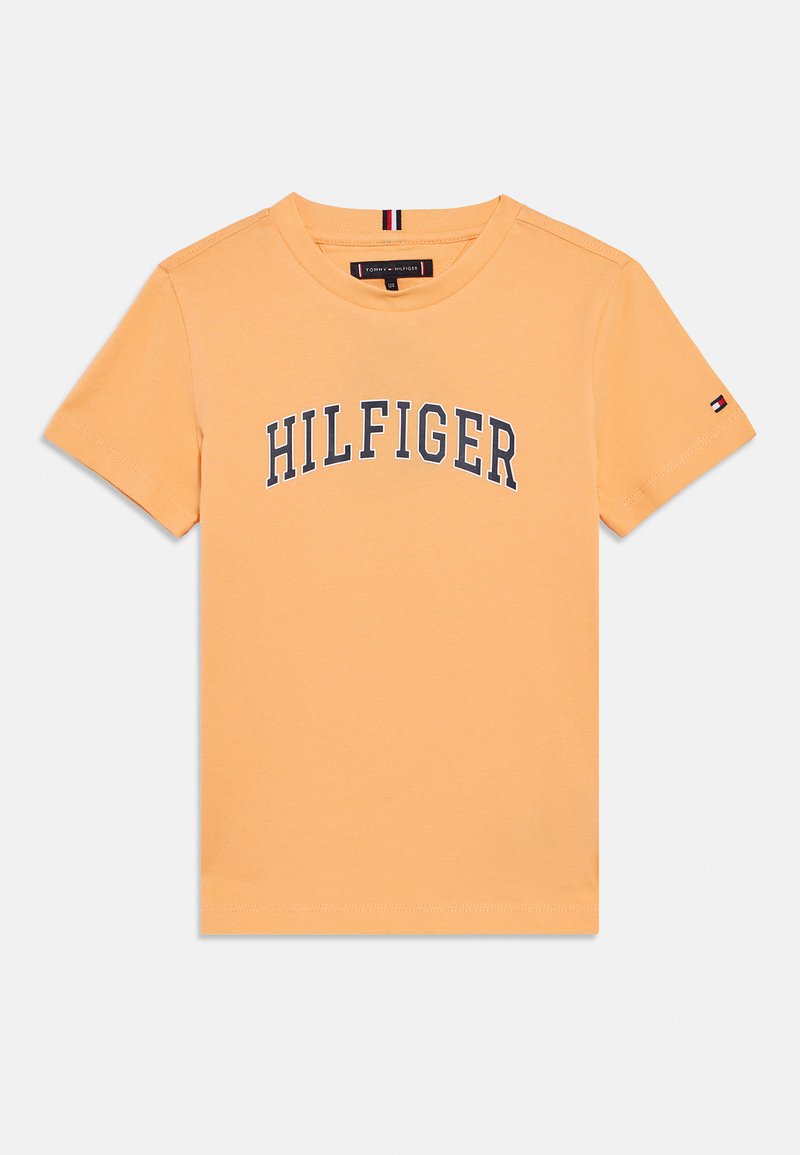 Πορτοκαλί βαμβακερό t-shirt με λογότυπο "HILFIGER" σε μπλε ναυτικό χρώμα κατά μήκος του στήθους, κοντά μανίκια και μικρό λογότυπο στη αριστερή πλευρά του μανικιού.
