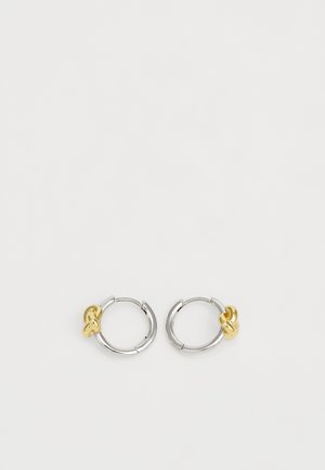 Sølvøreringe med en gylden knudeaccent. Øreringene er slanke og polerede, hvilket fremhæver et to-farvet design.