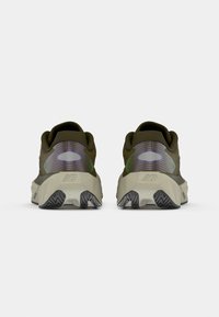 Zapatillas de malla verdes con un panel trasero texturizado, amortiguación marcada en el talón y suela de goma negra con patrones en zigzag.