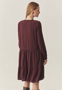 Bordo kleit geomeetrilise mustriga, pikkade varrukatega, kihilise seeliku ja lõdva lõikega. Omab ümmargust kaelust ja elastset vööd.