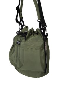 Green nylon handbag with a drawstring top, adjustable straps, front zip pocket, and branded tag, featuring a soft, textured finish.