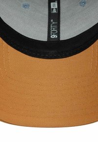 Brauner Hut mit einem schwarzen Schirm und einem strukturierten Stoff. Verfügt über ein graues Innenfutter mit dem 9FORTY-Logo, das innen gestickt ist.