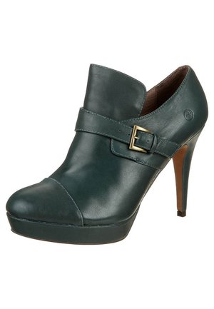 Bottine à talon haut en cuir vert foncé avec bout arrondi, semelle compensée et bride à boucle dorée à l'avant.