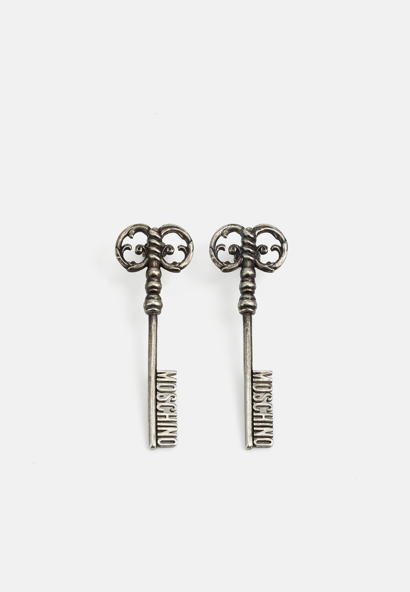 Pair of silver ornate vintage-style keys with "MOSCHINO" lettering on the shaft against a plain white background.