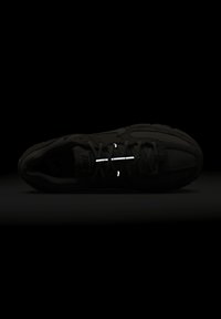 Fekete sportcipő strukturált textil felsőrésszel, fényvisszaverő fűzőkkel és lekerekített orrformával. Minimalista stílus, varrat nélküli megjelenéssel.