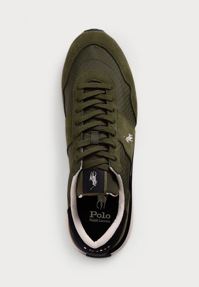Olive green sneaker with a textured upper, suede accents, and black details. Features a lace-up front and a logo on the tongue.