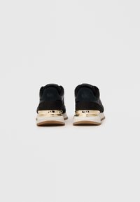 Dvojica čiernych tenisiek so zlatými detailami na päte zobrazených zozadu na bielom pozadí.