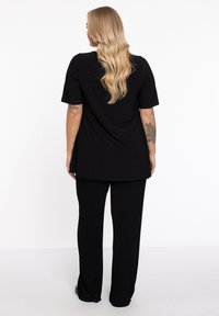 Zwart t-shirt en broekset, met een ontspannen ontwerp, korte mouwen en ribbelstructuur op de broek met zijsplitten.