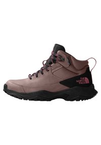 Bota de senderismo de corte medio en marrón claro con acentos negros. Presenta una parte superior sintética texturizada, cordones rosas y una suela exterior de caucho negro duradero.