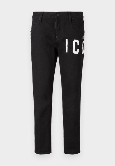 Jean en denim noir à coupe slim. Présente un texte graphique blanc sur le devant, cinq poches et un bouton de fermeture. Texture lisse.