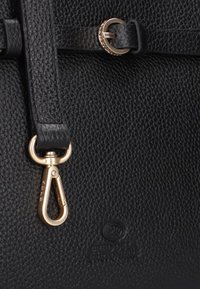 Zwarte gestructureerde leren tas met gouden hardware, uitgerust met een sluiting en een logo dat aan de onderkant is geperst. Het ontwerp bevat dunne banden en een gladde afwerking.