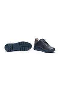 Zapatos de cuero negro con puntera redondeada y cierre de cordones, que cuentan con una suela de goma texturada y acentos lisos a lo largo del costado.