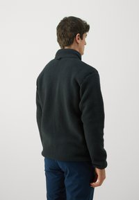 Pullover in fleece con colletto alto di colore grigio scuro. Texture morbida, vestibilità comoda e polsini elasticizzati. La vista posteriore mostra un design minimalista.