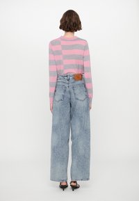 Light gray and pink striped long-sleeve shirt paired with high-waisted, wide-leg light blue jeans featuring a brown leather patch.